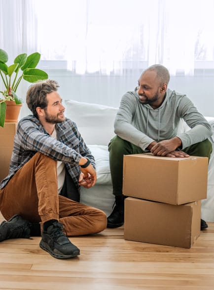 Deux hommes assis devant des cartons de déménagement