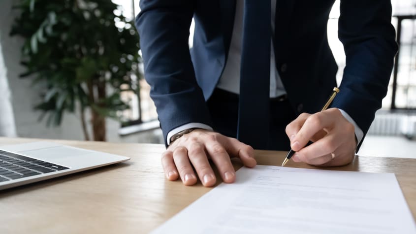 Close-up of a person signing a contract for a transaction